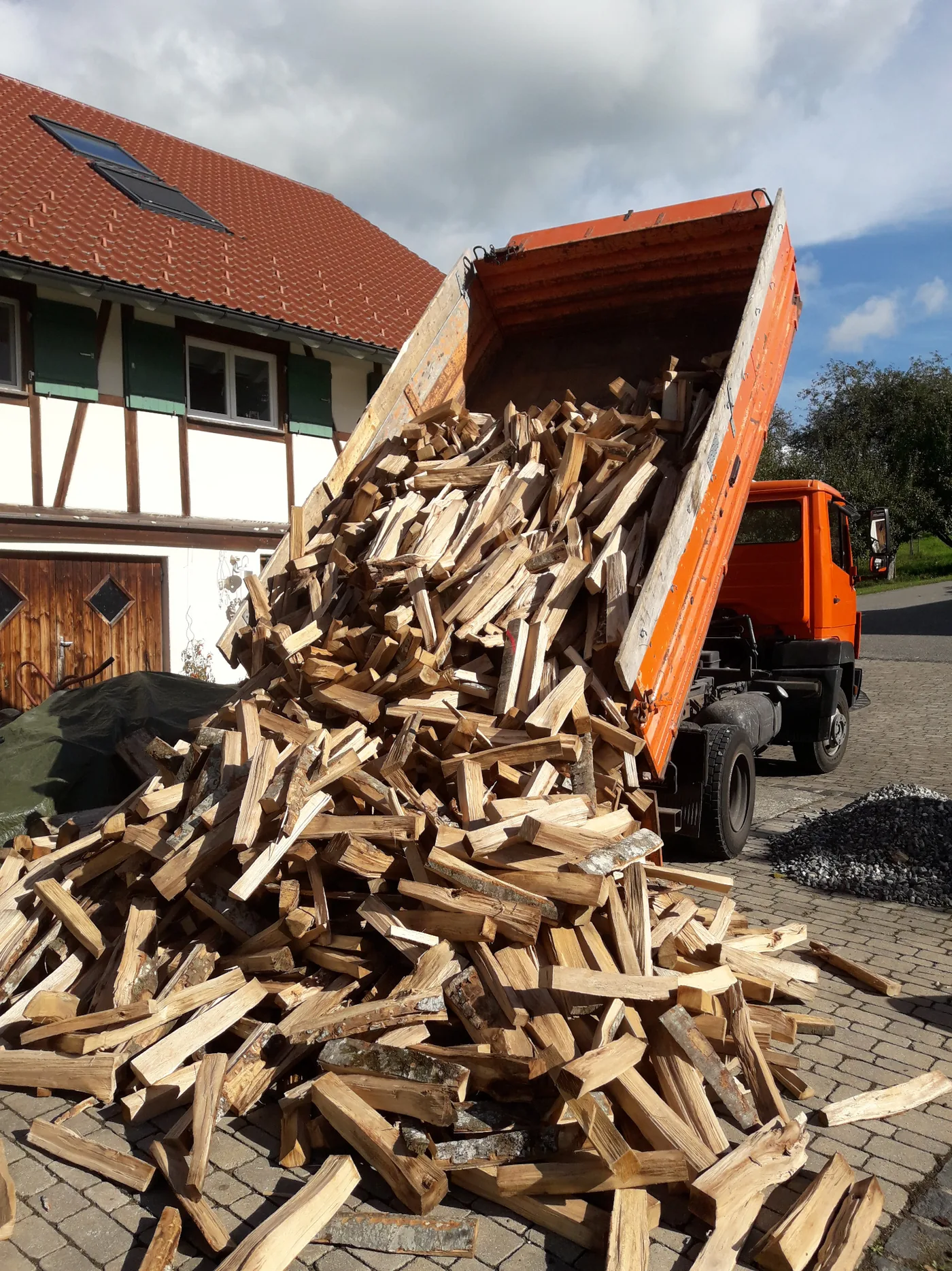 Brennholz wird bei einer Lieferung abgekippt